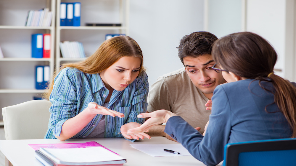 Young family disappointed by mortgage application denial at brokers office.