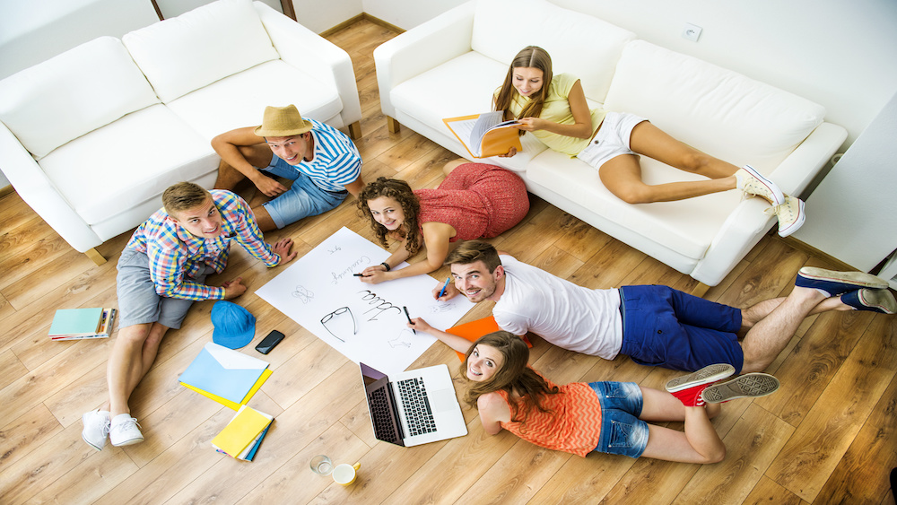 Group of college co-eds in studying and socializing in safe student housing.