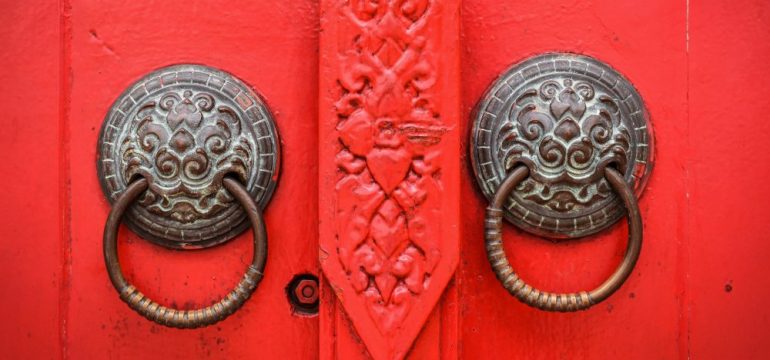 Vintage brass cabinet hardware on a red decorative door.