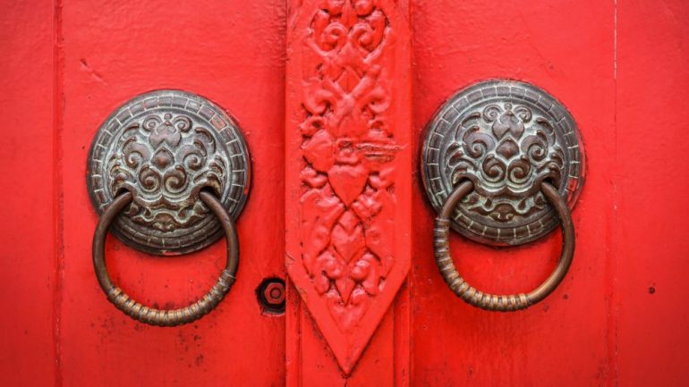 Vintage brass cabinet hardware on a red decorative door.