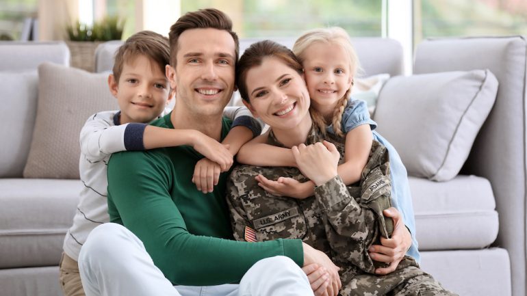 Veterans or active military represented by a woman in uniform with her family at home.