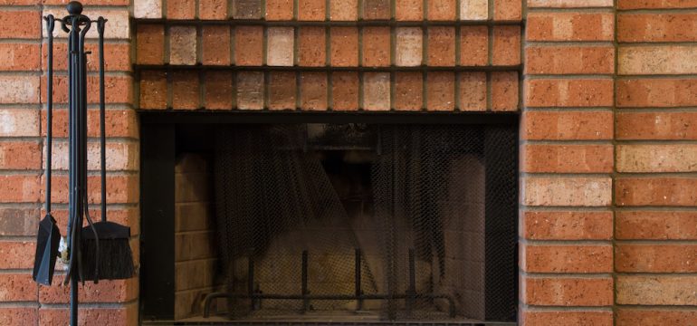 Old red brick fireplace with accessories.