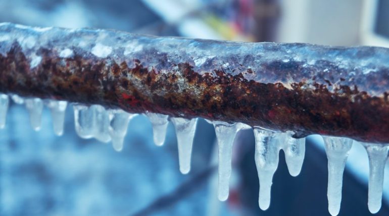 Many small icicles on a frozen pipes during the winter.