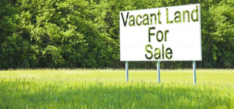 Billboard in green grass advertising rural land for sale.