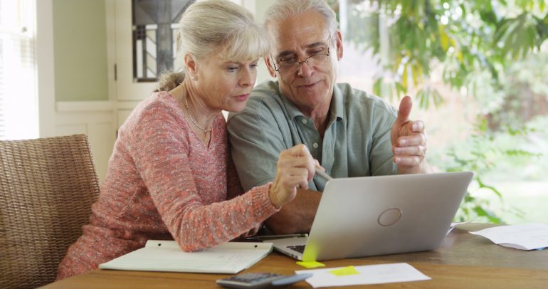 Senior couple using laptop to browse an online real estate marketplace looking to buy a home.