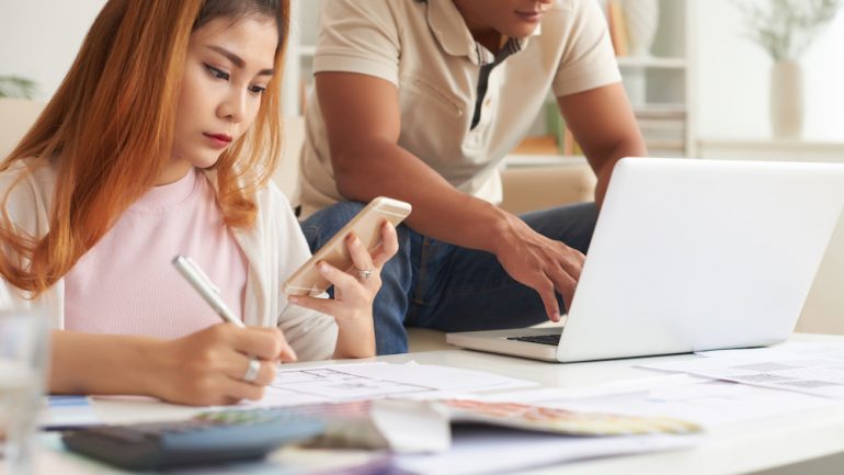 Portrait of modern couple planning budget for mortgage points and loan costs to buy new house.