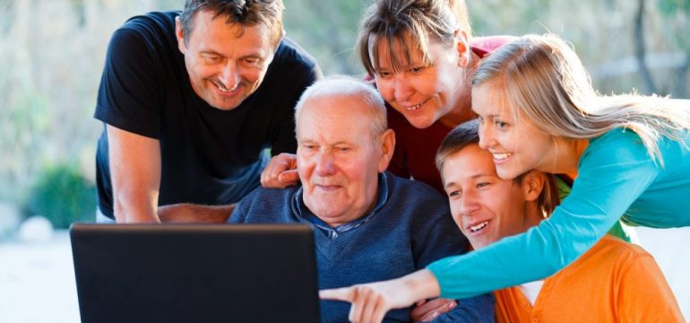 Three generations of a family are looking at homes for sale on laptop.