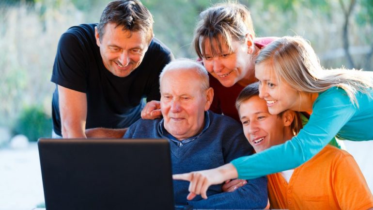 Three generations of a family are looking at homes for sale on laptop.