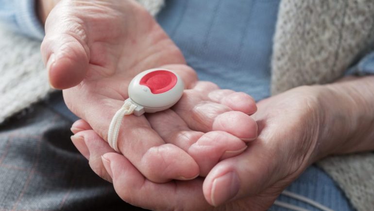 Senior citizen holding a medical alert device in their hands.