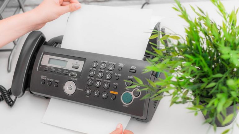 Person sending faxes from home office fax machine.