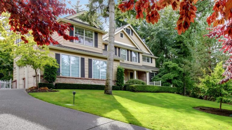 Beautiful large beige home on the hill surrounded by energy efficient landscaping.