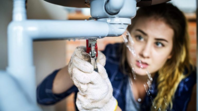 First-time homeowners fixing the kitchen sink.