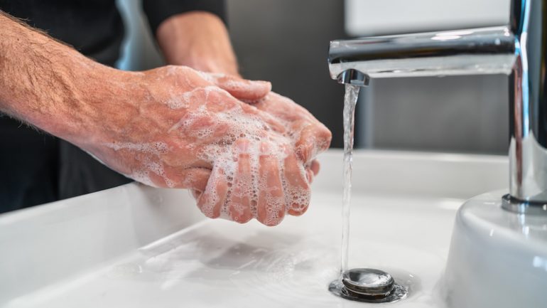 Coronavirus prevention showing hand washing with soap in hot water to prevent spread of virus in the home.