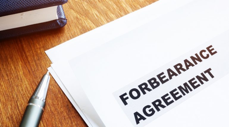 Mortgage forbearance agreement papers with pen and notepad.