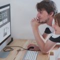 A couple conducting a online home search on a real estate portal on their home desktop computer.