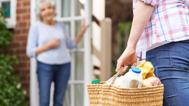 Young woman bringing groceries to her elderly neighbors.