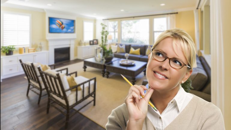 Daydreaming woman with pencil inside beautiful living room designed with virtual home staging tools.