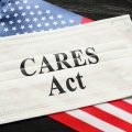 American flag and mask with sign of the Cares Act. Concept of how the relief affects a person's credit.