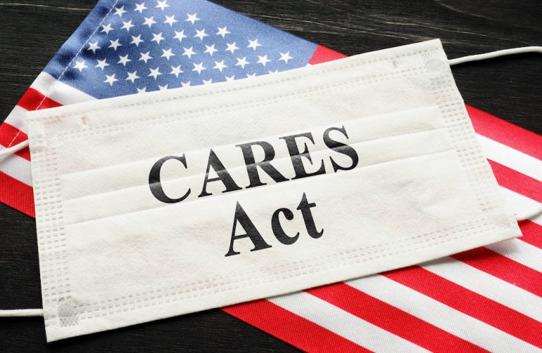 American flag and mask with sign of the Cares Act. Concept of how the relief affects a person's credit.