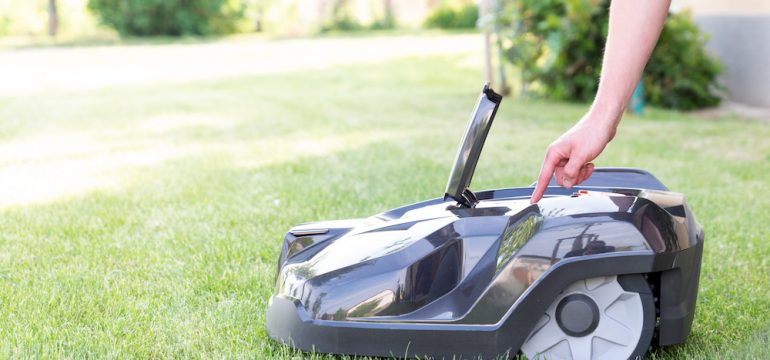 Man starting up a robotic lawn mower that is an example of outdoor smart home technology.