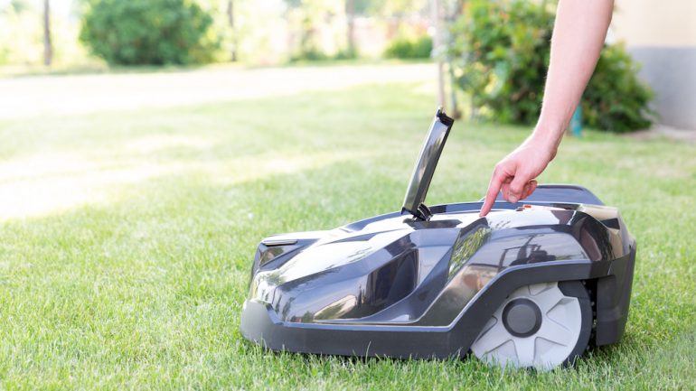 Man starting up a robotic lawn mower that is an example of outdoor smart home technology.