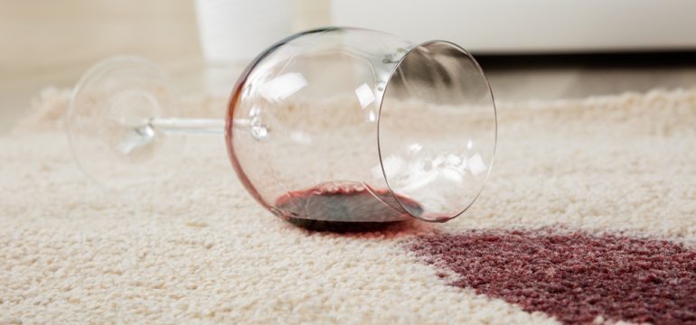 High Angle View Of Red Wine Spilled From Glass On Carpet to Show Concept of DIY Carpet Repair.