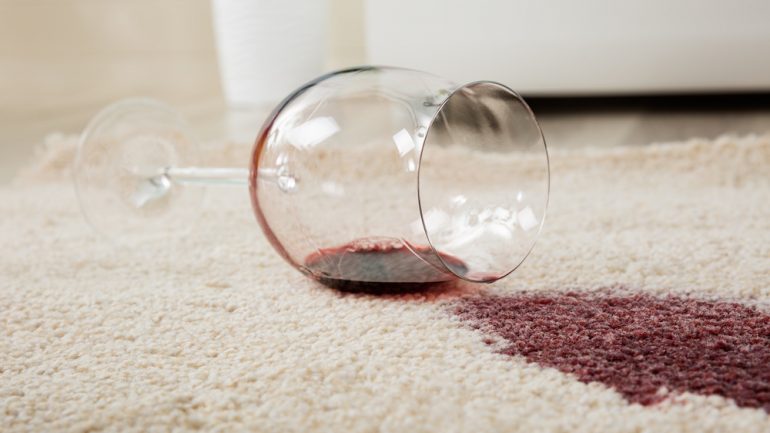 High Angle View Of Red Wine Spilled From Glass On Carpet to Show Concept of DIY Carpet Repair.