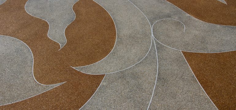 Decorative concrete floor close up with beige and grey swirl pattern.