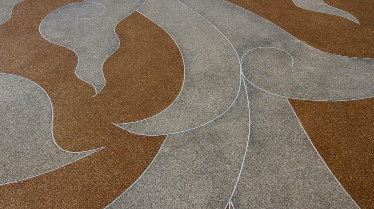 Decorative concrete floor close up with beige and grey swirl pattern.