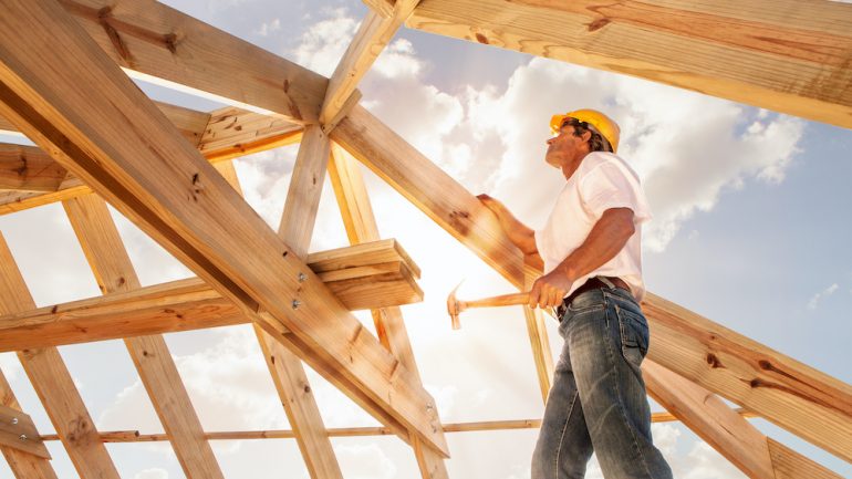 Homebuilder working on framing a roof for a new construction home.