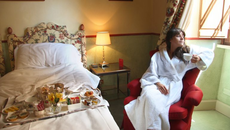 Woman gazing out the window from her room at a bed-and-breakfast inn.