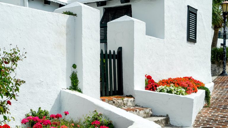 Brilliant flowerbeds along the stucco walls of foreign real estate in Bermuda.