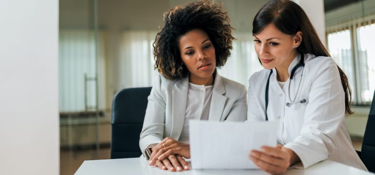 Portrait of a female health care provider and new female patient reviewing test results.