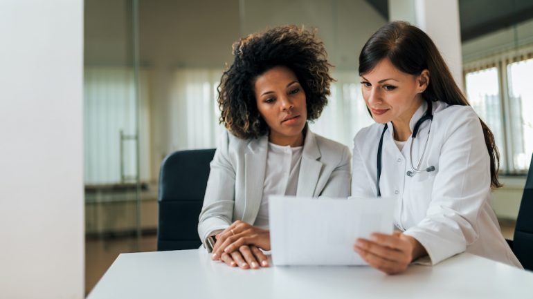 Portrait of a female health care provider and new female patient reviewing test results.