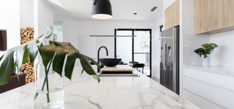 Kitchen marble bench close up with black hanging pendant and vase.
