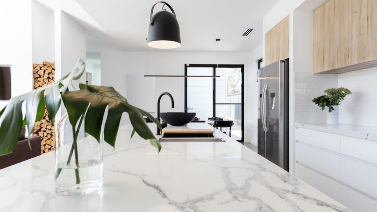 Kitchen marble bench close up with black hanging pendant and vase.