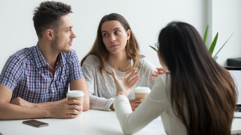 Couple looking at each other doubting offer from instant buyer.