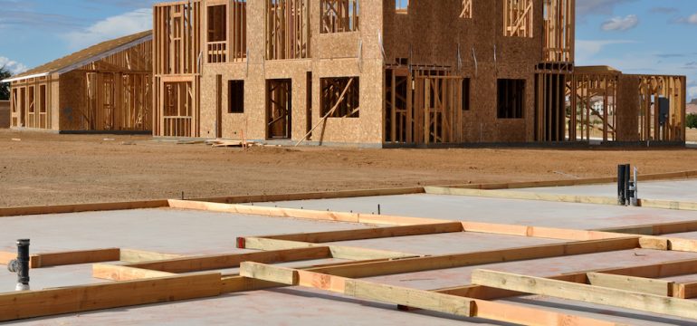 New house foundations in foreground with other homes framed and under construction in the background.