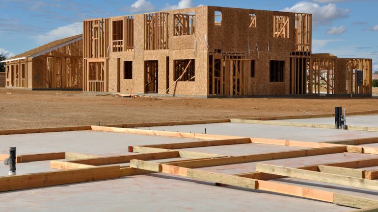 New house foundations in foreground with other homes framed and under construction in the background.