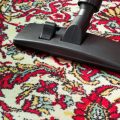 Photo showing how to properly vacuum clean area rugs. Vacuum cleaner universal nozzle moving across oriental rug.