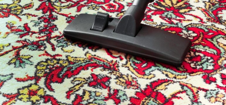 Photo showing how to properly vacuum clean area rugs. Vacuum cleaner universal nozzle moving across oriental rug.