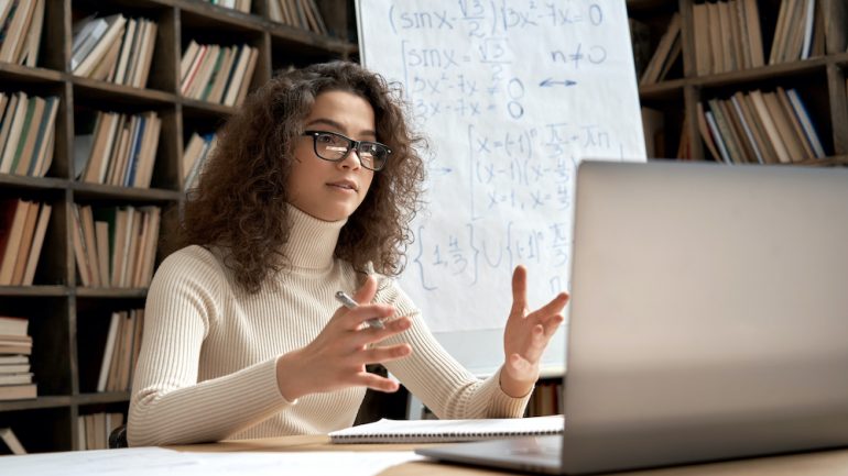 Female hispanic school math teacher virtual teaching by Zoom conference call.