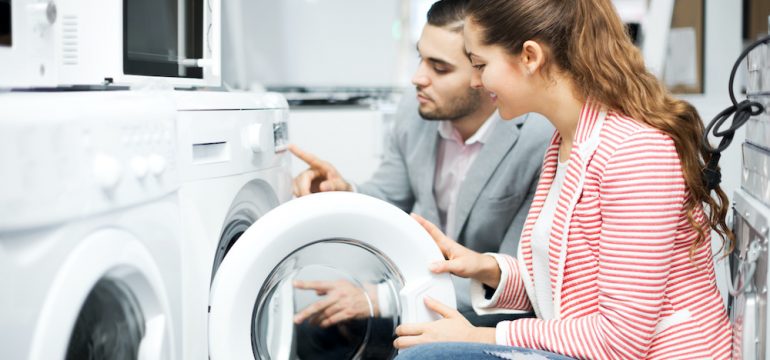 Young couple buying new clothes washer to move abroad.