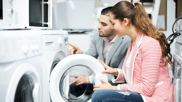 Young couple buying new clothes washer to move abroad.