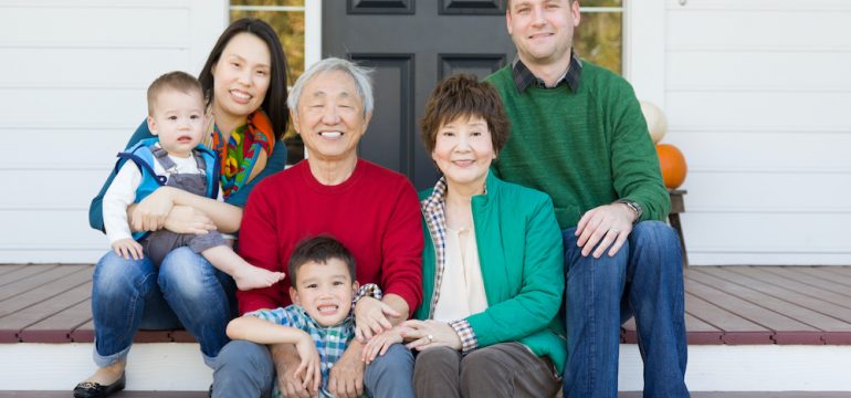 Multigenerational Chinese and Caucasian family portrait sitting on the front stairs of a home.