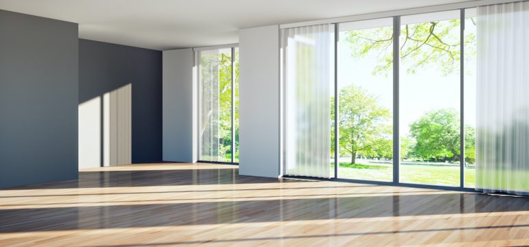 Vacant home living room with floor to ceiling windows.