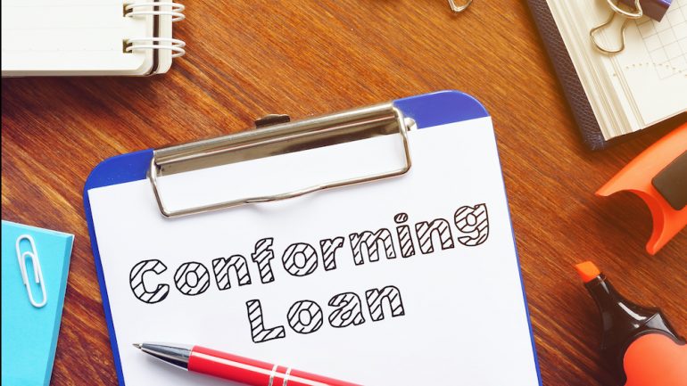 Conforming loan is shown on the conceptual business photo of a clip board with a document and pencil on a desk.