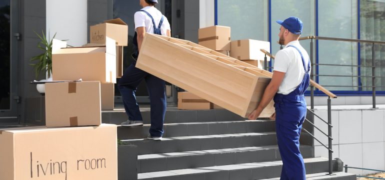 Male movers carrying shelving unit into new house. Concept of avoiding rogue moving companies.