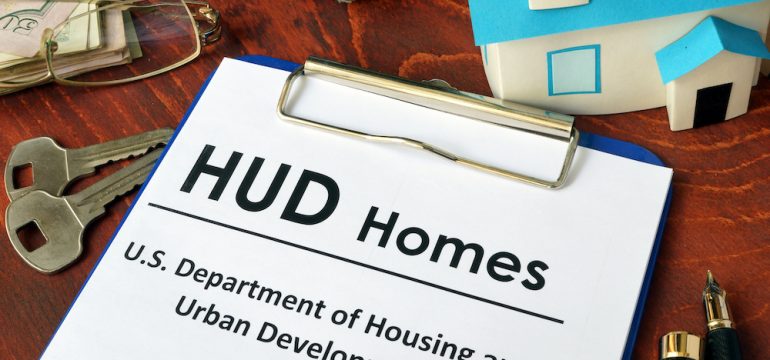 Paper referring to HUD foreclosure homes on a wooden surface.