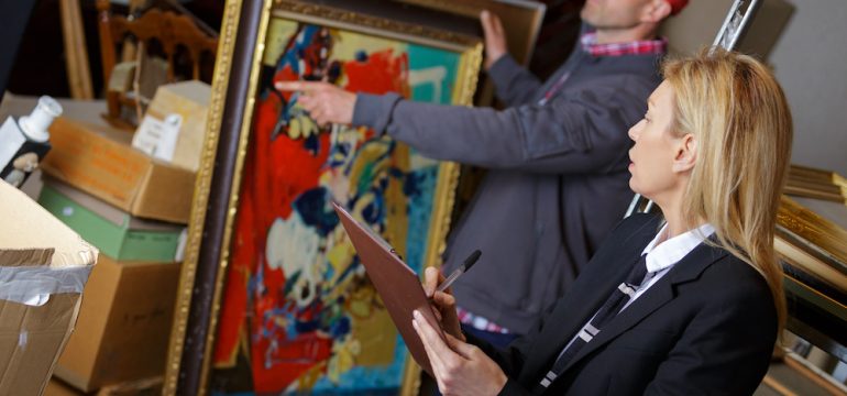 Women working with vendor to sell antiques including a bright colored painting.